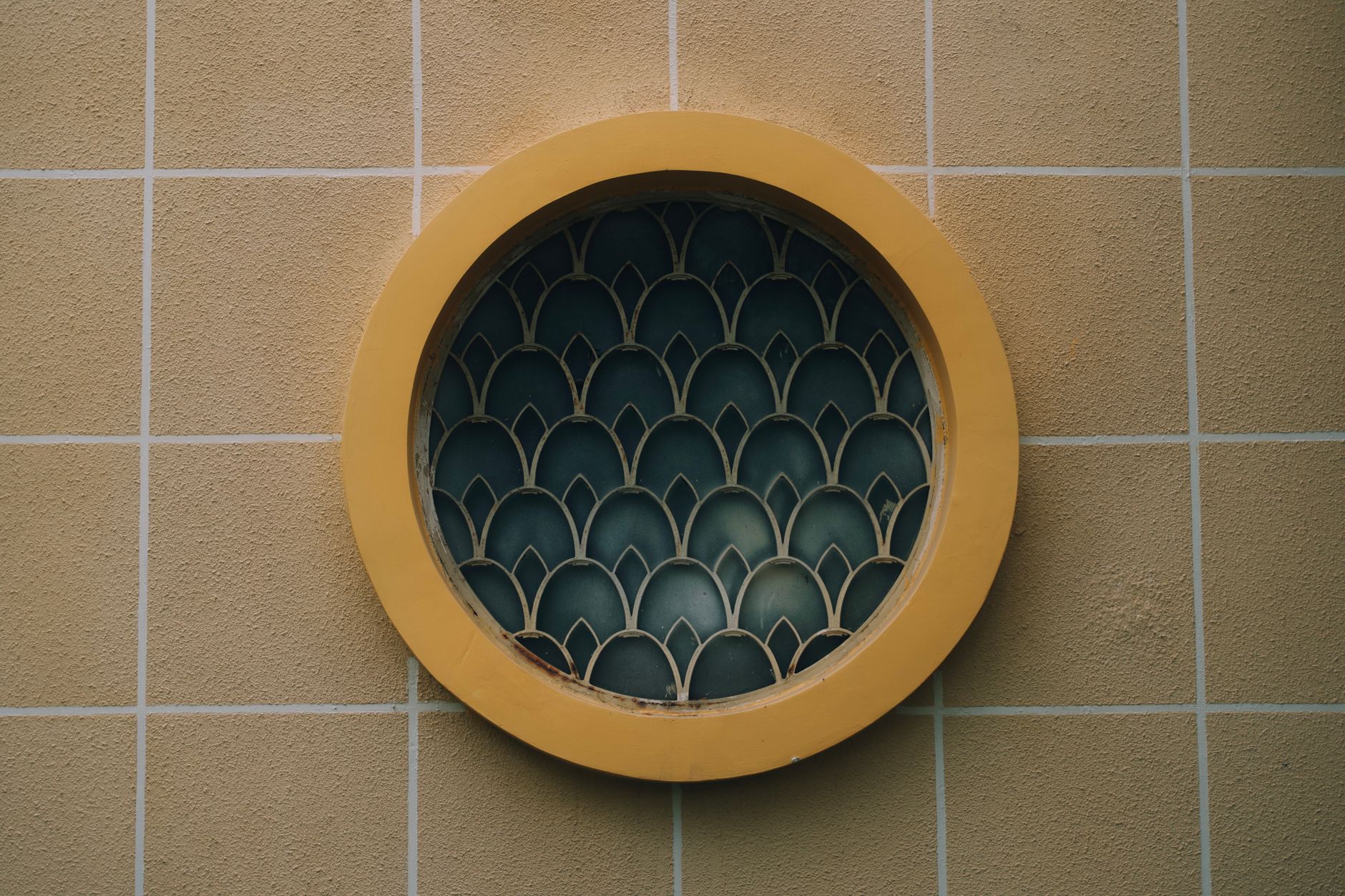 round window with decorative grille on tiled wall